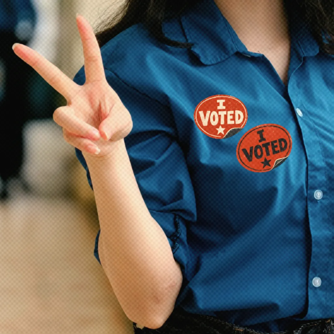 A woman wearing two "I VOTED" stickers holding up a peace sign with her hand.