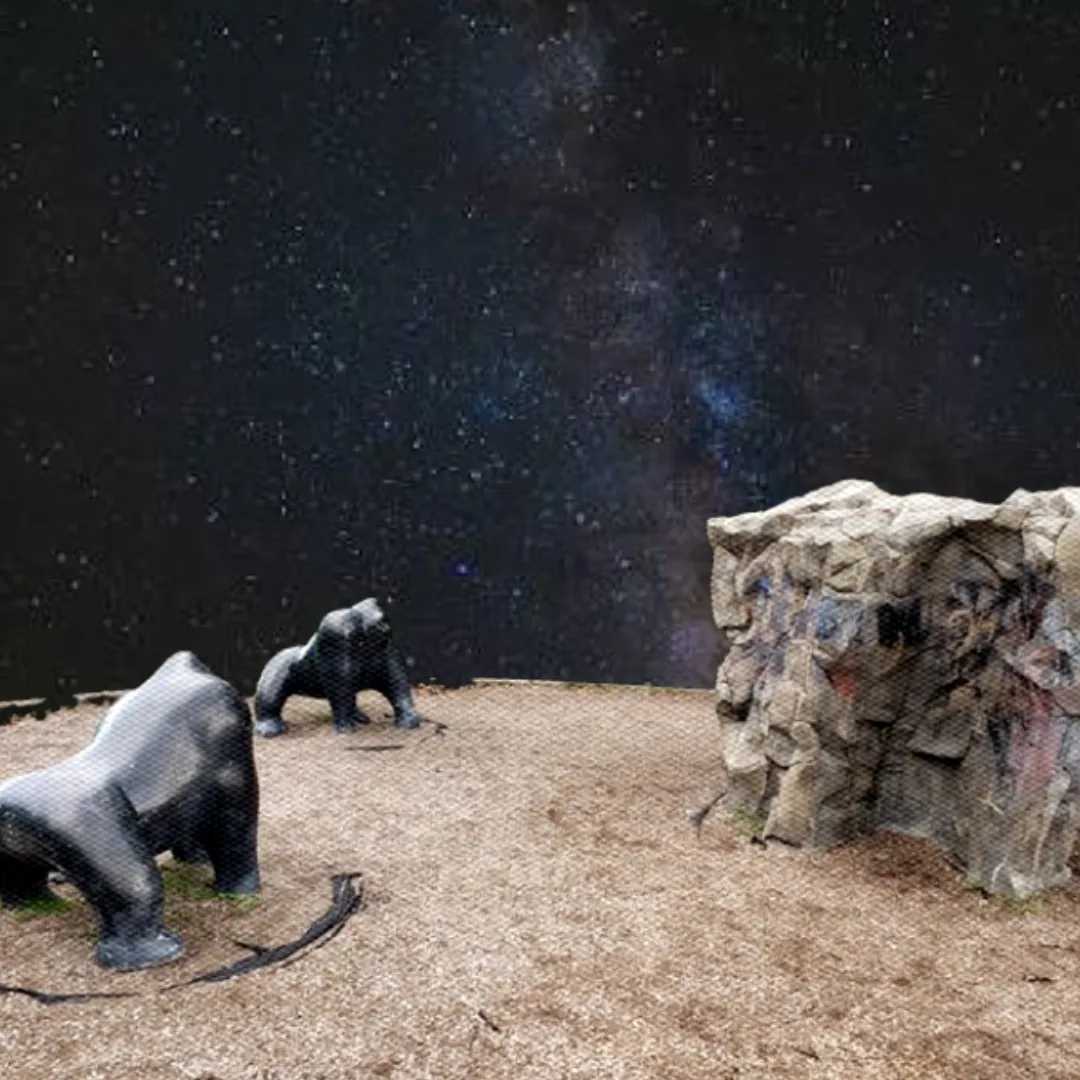 Two gorilla statues staring at a boulder with an outer space background.
